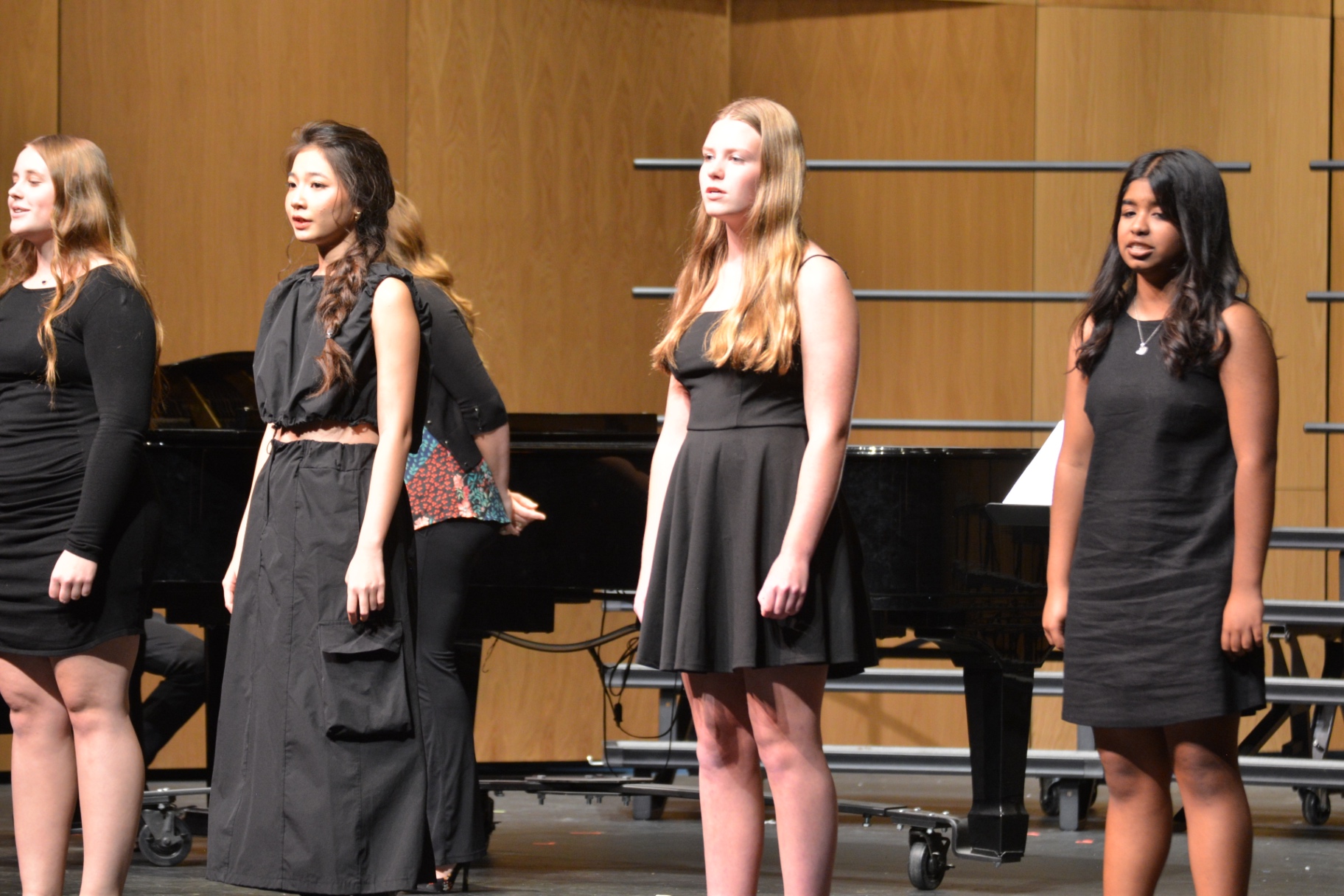 Vocal ensemble students singing beside a grand piano
